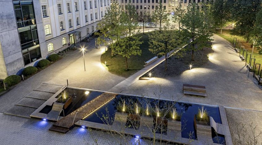 Beleuchteter öffentlicher Platz mit Wasseranlage